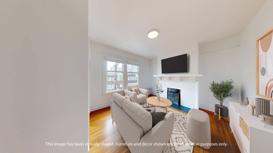 A living room with a grey couch, a small table, a television, and a fireplace.